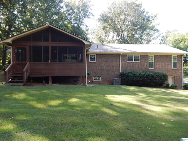 rear view of house with central AC unit, a sunroom, and a yard