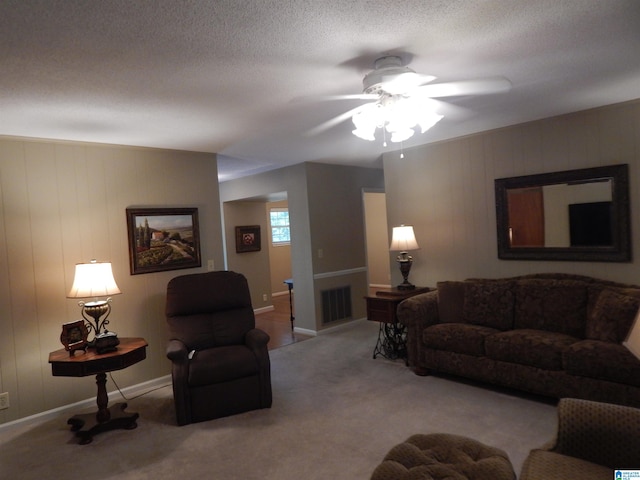 living room with ceiling fan, light colored carpet, and a textured ceiling