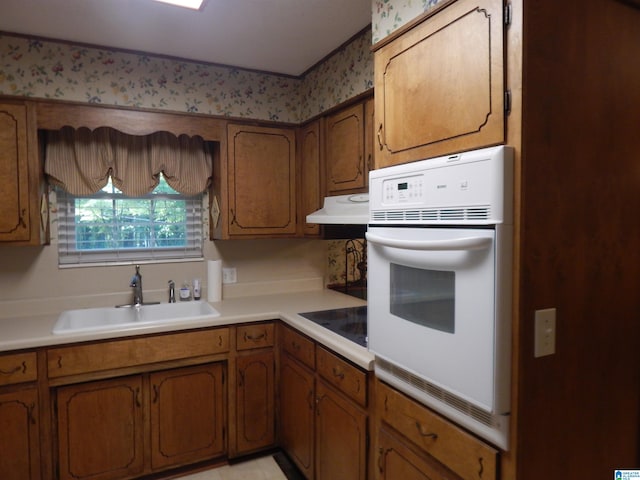 kitchen with black electric stovetop, oven, and sink