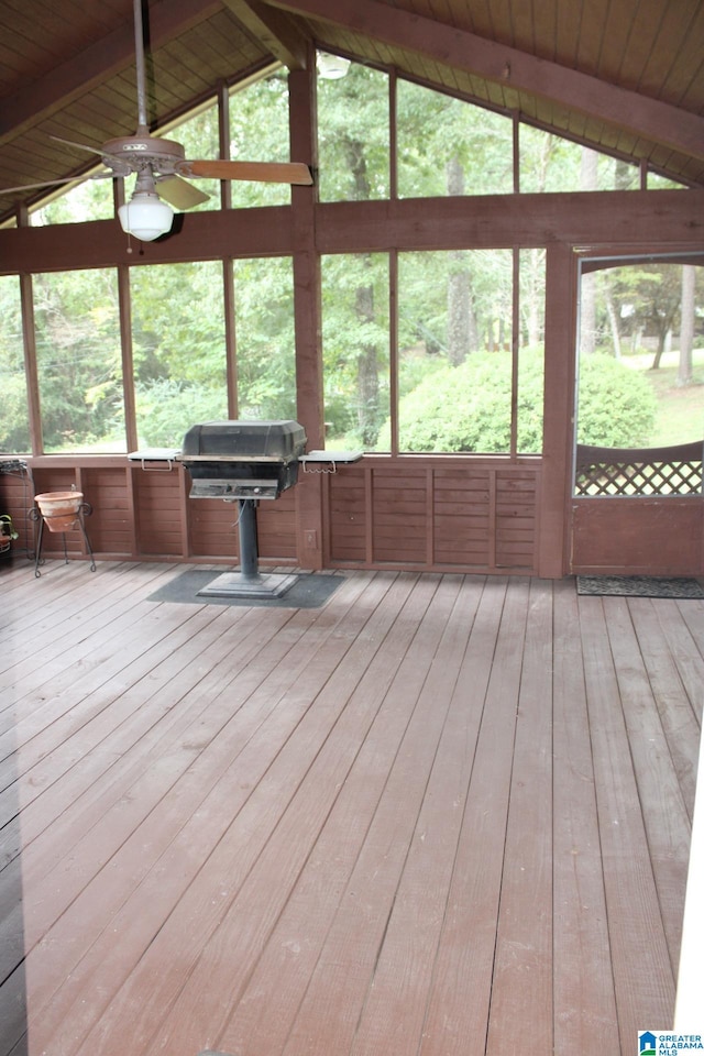 unfurnished sunroom featuring lofted ceiling with beams, ceiling fan, and plenty of natural light