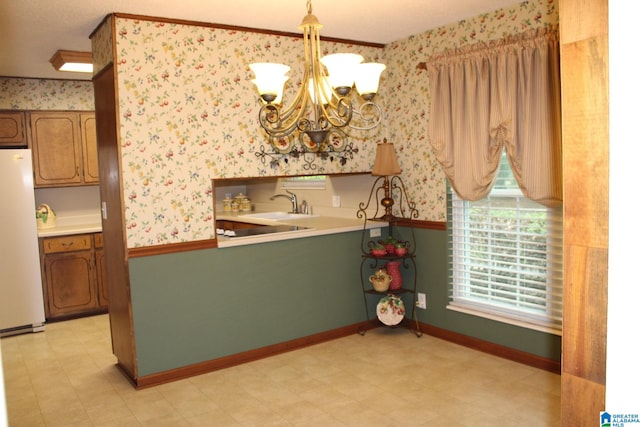 interior space featuring hanging light fixtures, white fridge, an inviting chandelier, ornamental molding, and sink