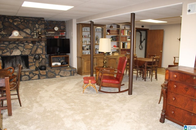 carpeted living room with a paneled ceiling and a stone fireplace