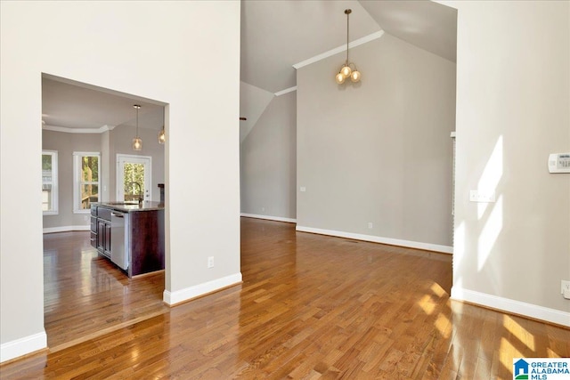 unfurnished room with crown molding, hardwood / wood-style floors, sink, and high vaulted ceiling