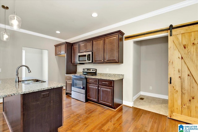 kitchen featuring light stone counters, pendant lighting, sink, stainless steel appliances, and light wood-type flooring