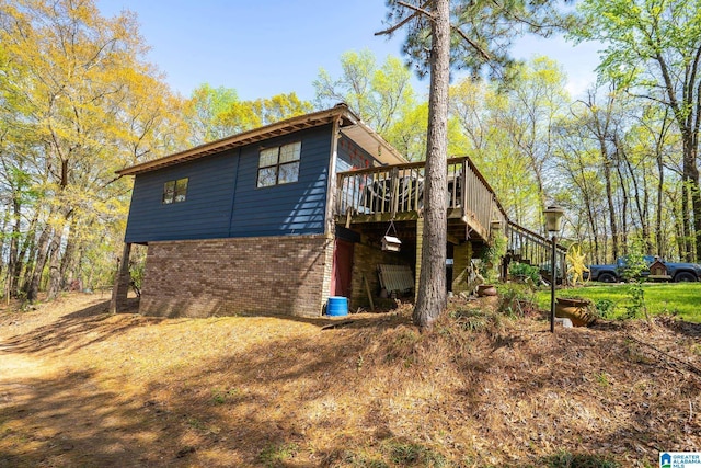 view of home's exterior with stairs, a wooden deck, and brick siding