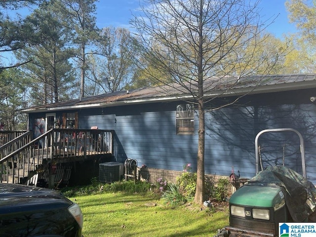 view of side of home featuring metal roof, a wooden deck, central AC, and a yard