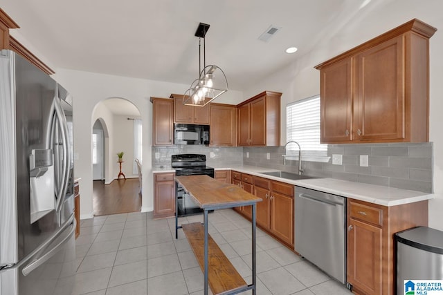 kitchen featuring black appliances, sink, pendant lighting, decorative backsplash, and light tile patterned floors