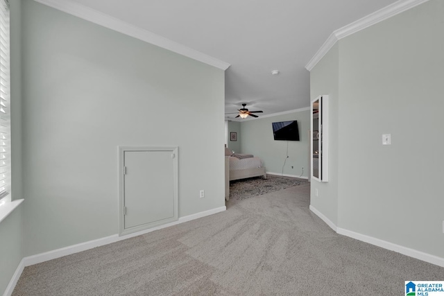 carpeted spare room featuring crown molding and ceiling fan