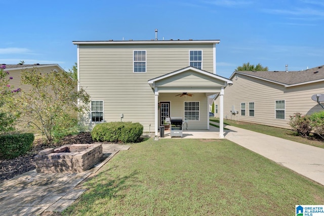 rear view of property featuring a patio, an outdoor fire pit, a lawn, and ceiling fan