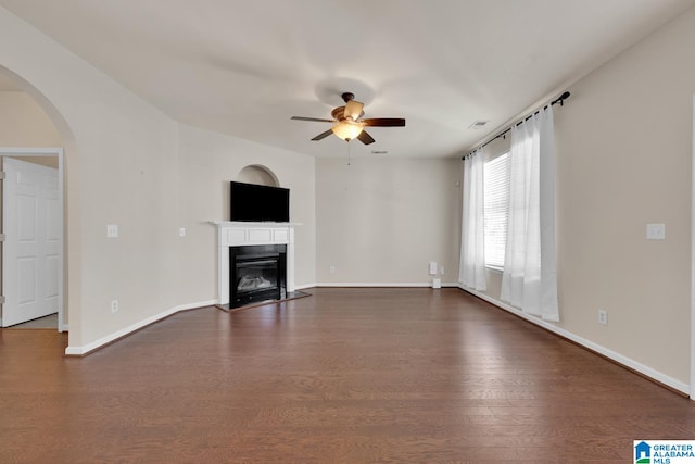 unfurnished living room featuring dark wood-type flooring and ceiling fan