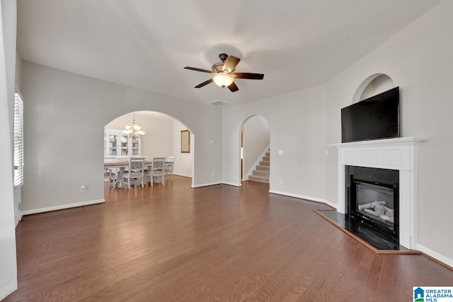 unfurnished living room featuring dark hardwood / wood-style flooring and ceiling fan with notable chandelier