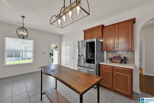 kitchen featuring stainless steel fridge, hanging light fixtures, backsplash, and light tile patterned floors