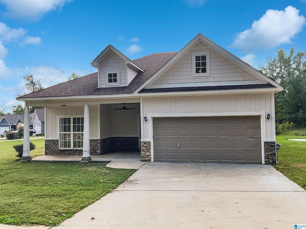 view of front of property with a front lawn, ceiling fan, and a garage