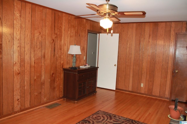 unfurnished bedroom featuring wooden walls, ceiling fan, and hardwood / wood-style flooring