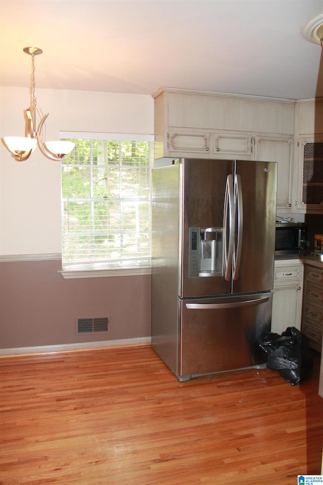 kitchen featuring pendant lighting, white cabinets, light hardwood / wood-style floors, and appliances with stainless steel finishes