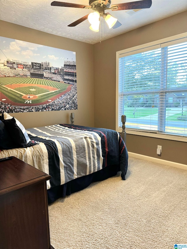 carpeted bedroom with ceiling fan, a textured ceiling, and multiple windows