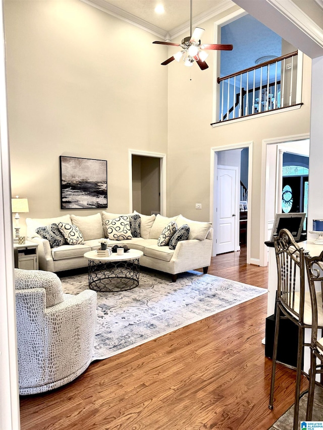 living room with crown molding, a high ceiling, dark hardwood / wood-style flooring, and ceiling fan