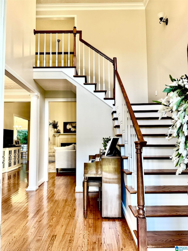 stairs with ornamental molding, decorative columns, and hardwood / wood-style floors