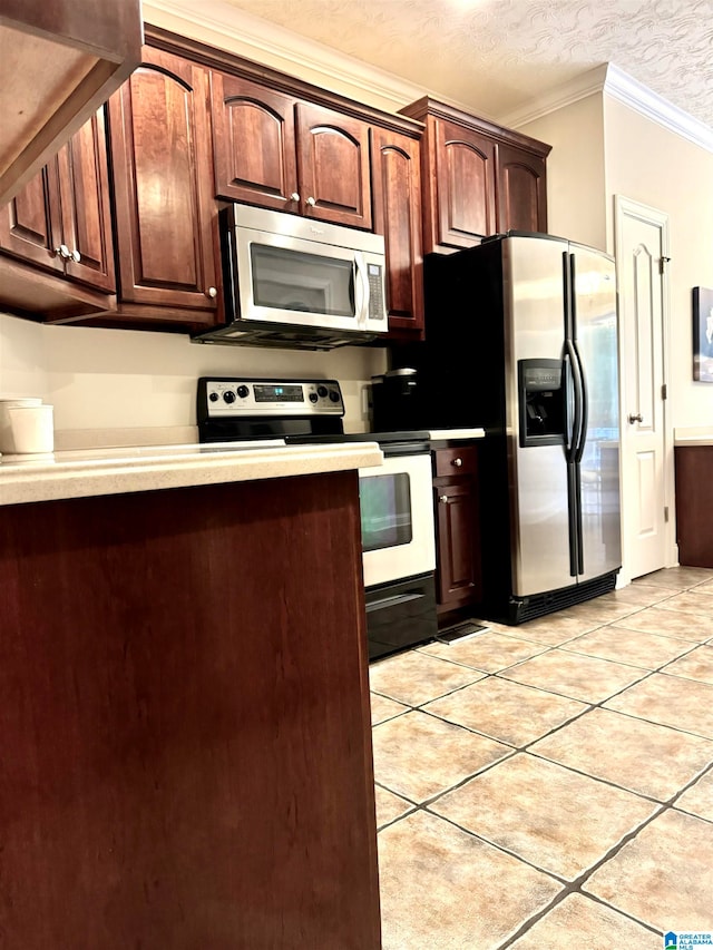 kitchen with a textured ceiling, appliances with stainless steel finishes, light tile patterned floors, and crown molding