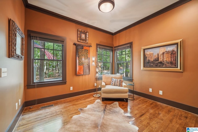 living area with crown molding and hardwood / wood-style flooring