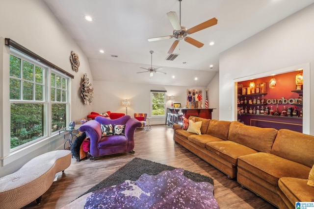 living room featuring bar, a wealth of natural light, vaulted ceiling, and wood-type flooring