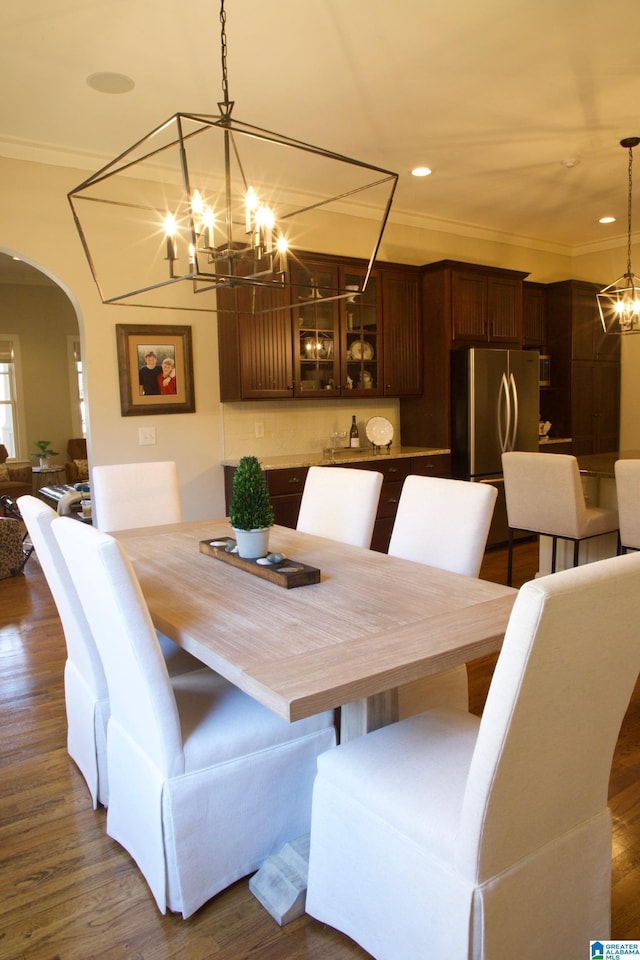 dining area featuring ornamental molding, dark wood-type flooring, and a notable chandelier