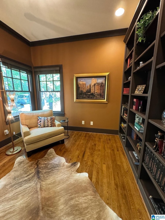 living area with hardwood / wood-style flooring and ornamental molding