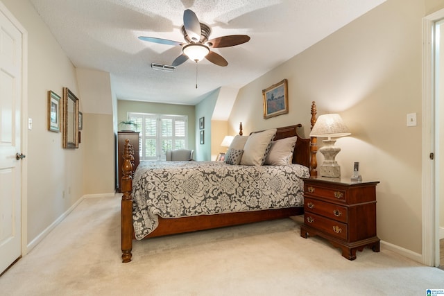 bedroom with ceiling fan, light colored carpet, and a textured ceiling