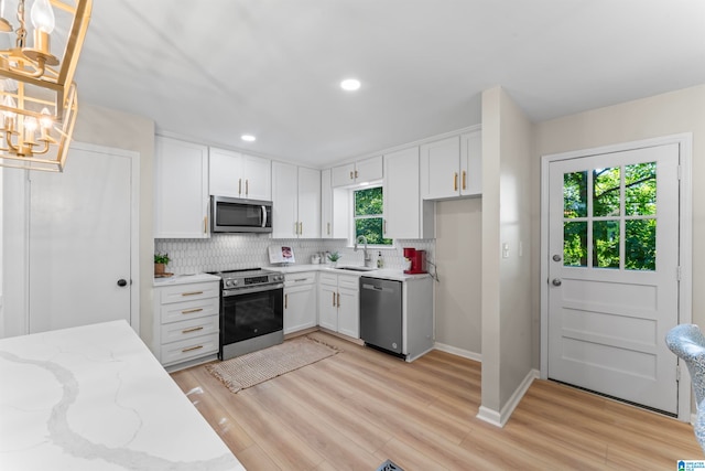 kitchen featuring stainless steel appliances, white cabinetry, hanging light fixtures, and sink