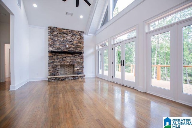 unfurnished living room with high vaulted ceiling, visible vents, baseboards, wood finished floors, and a ceiling fan