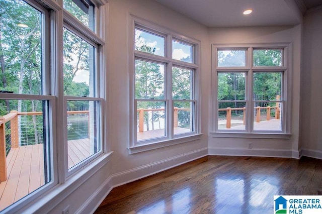 unfurnished sunroom featuring plenty of natural light, baseboards, wood finished floors, and recessed lighting