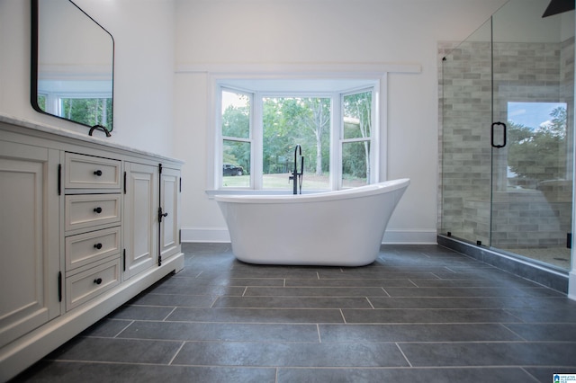 bathroom with baseboards, vanity, a freestanding tub, and a shower stall