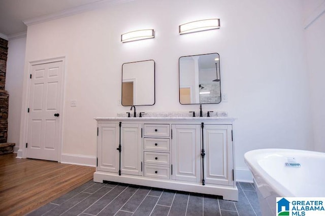 full bathroom with ornamental molding, a sink, a freestanding tub, and wood finished floors