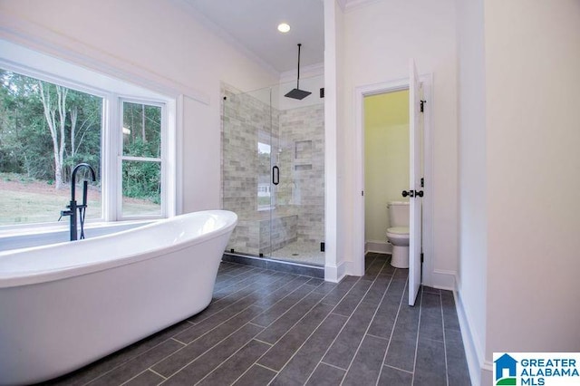 full bath featuring baseboards, toilet, a freestanding tub, wood finished floors, and a stall shower
