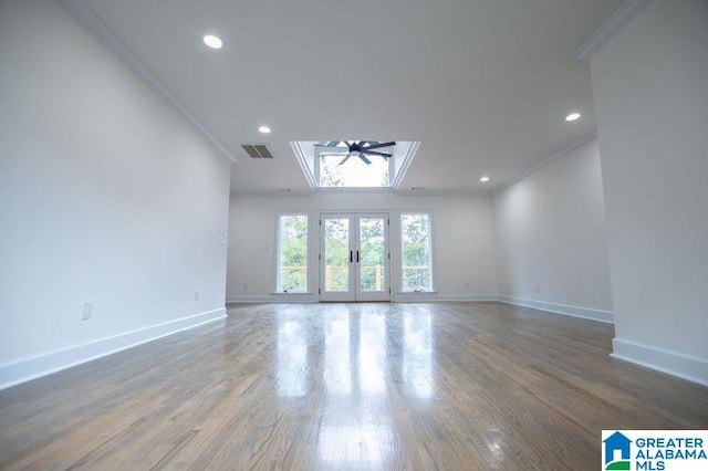 empty room featuring visible vents, baseboards, ornamental molding, wood finished floors, and french doors