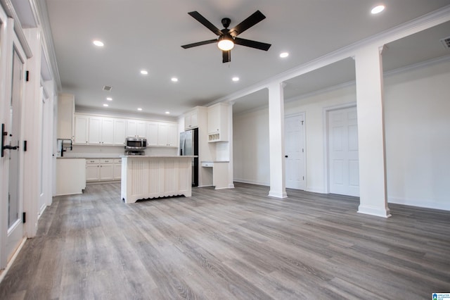 kitchen featuring appliances with stainless steel finishes, open floor plan, light wood-style floors, ornamental molding, and recessed lighting