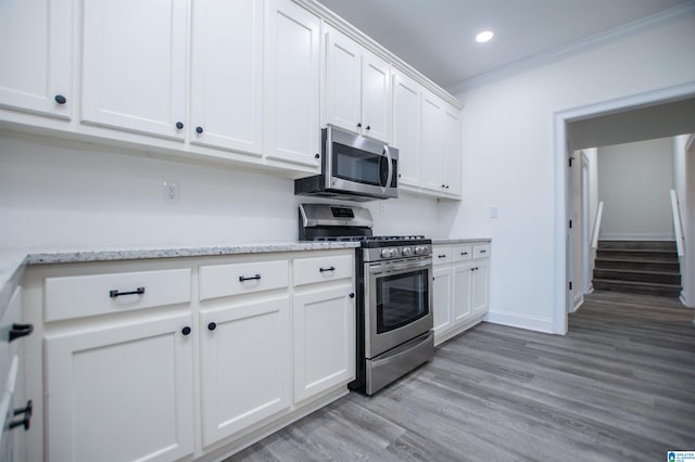 kitchen with white cabinetry, appliances with stainless steel finishes, light wood-style floors, ornamental molding, and recessed lighting