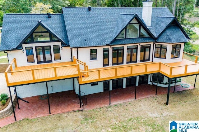 rear view of property featuring a chimney, a patio area, and roof with shingles
