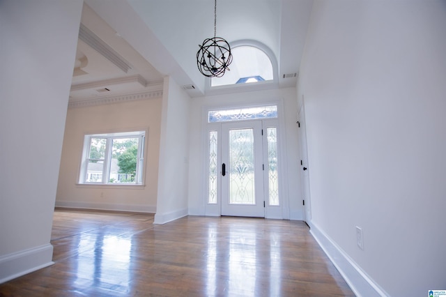 entrance foyer with an inviting chandelier, a tray ceiling, baseboards, and wood finished floors