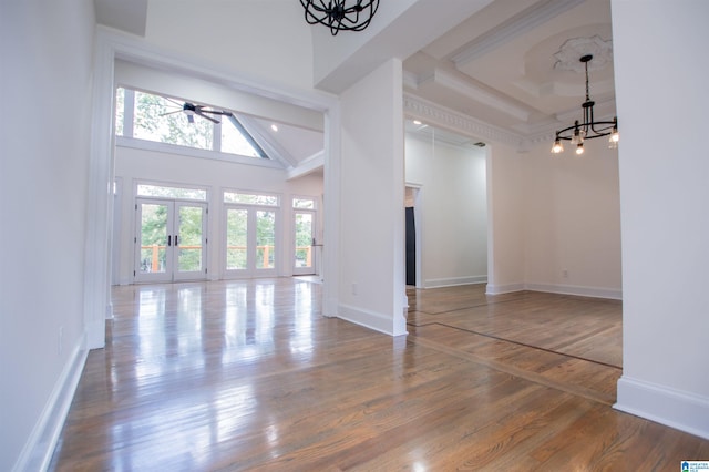 interior space with baseboards, a high ceiling, a chandelier, and wood finished floors