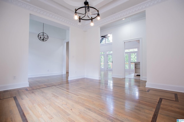 unfurnished room with a tray ceiling, french doors, a high ceiling, wood finished floors, and baseboards