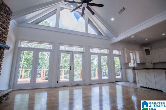 unfurnished living room with a wealth of natural light, visible vents, ceiling fan, and french doors