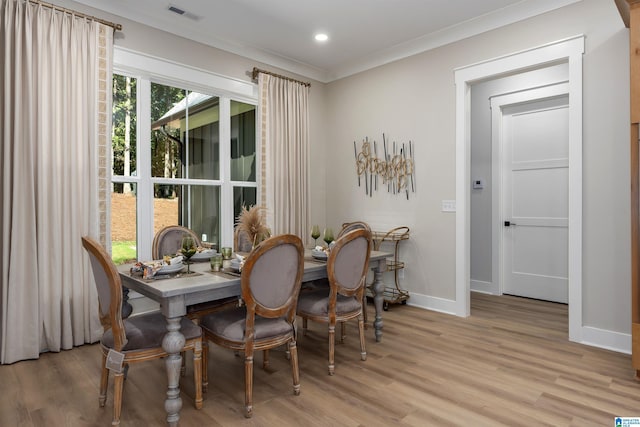 dining space featuring light wood-style flooring, crown molding, baseboards, and visible vents