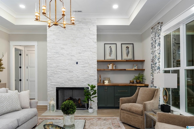 living area featuring ornamental molding, visible vents, a raised ceiling, and light wood-style floors