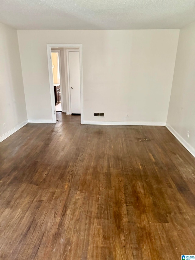 empty room with dark wood-type flooring and a textured ceiling