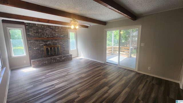 unfurnished living room with a brick fireplace, ceiling fan, plenty of natural light, and dark wood-type flooring