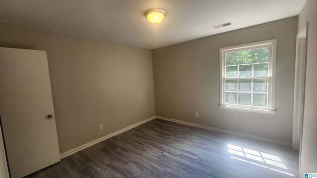unfurnished room featuring visible vents, baseboards, and dark wood finished floors