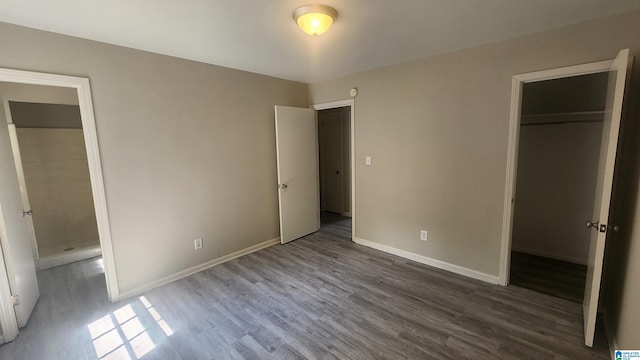 unfurnished bedroom featuring a spacious closet, a closet, baseboards, and wood finished floors