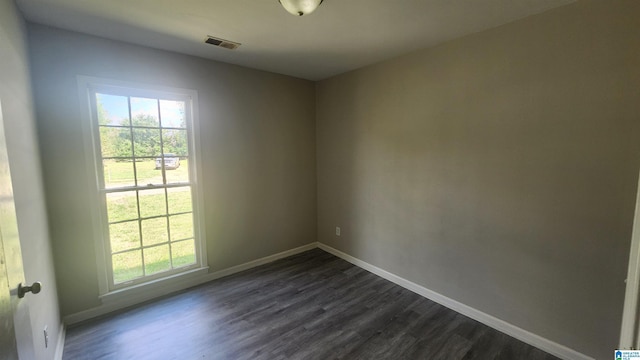 unfurnished room with dark wood-type flooring, a healthy amount of sunlight, and visible vents
