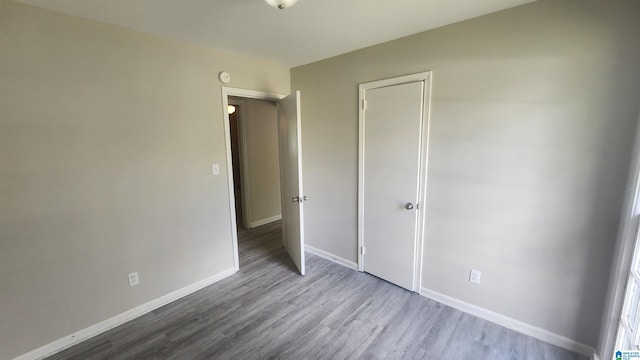 unfurnished bedroom featuring a closet, baseboards, and wood finished floors